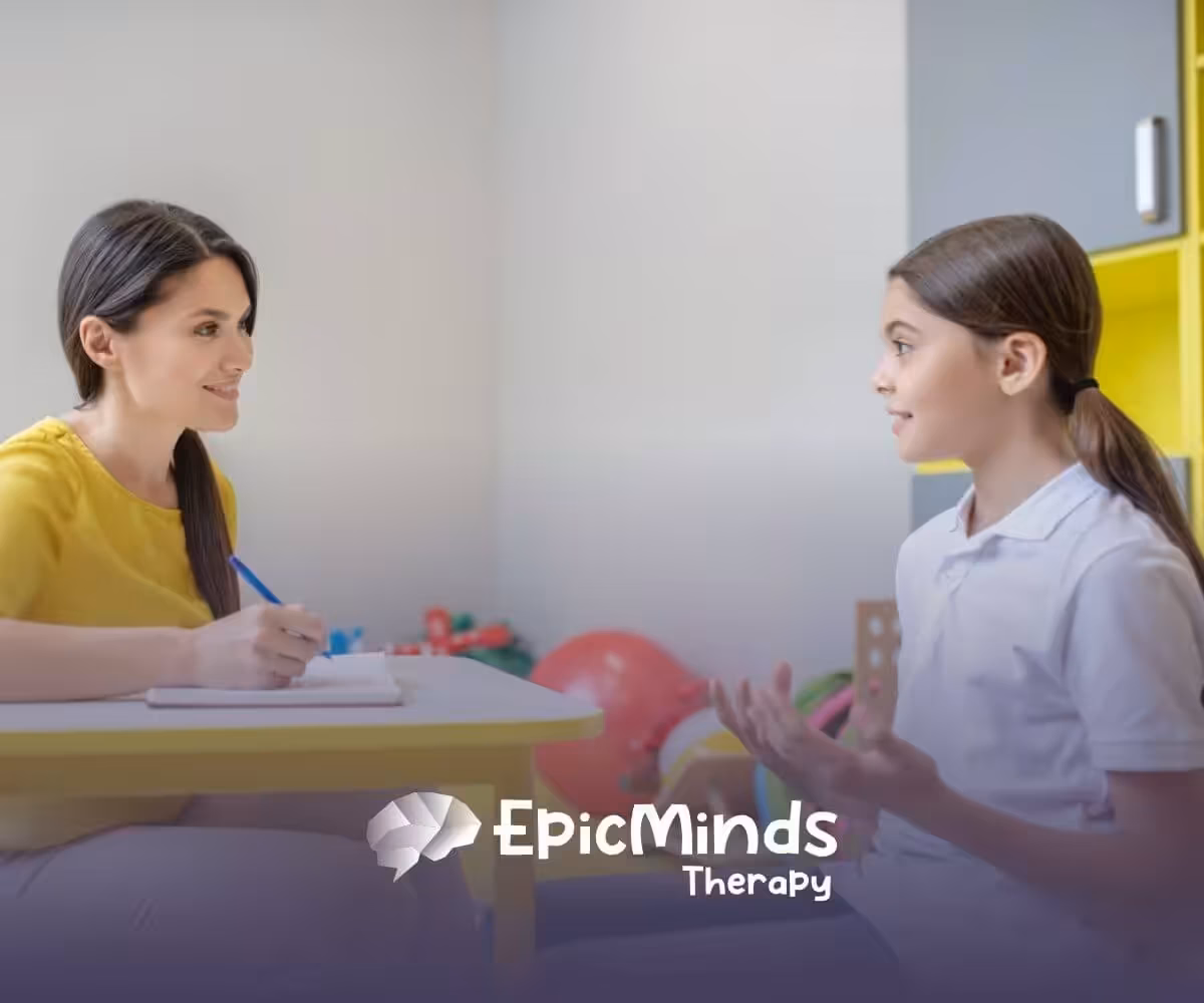 ABA therapist and a child engage in a conversation while sitting at a table during ABA therapy.