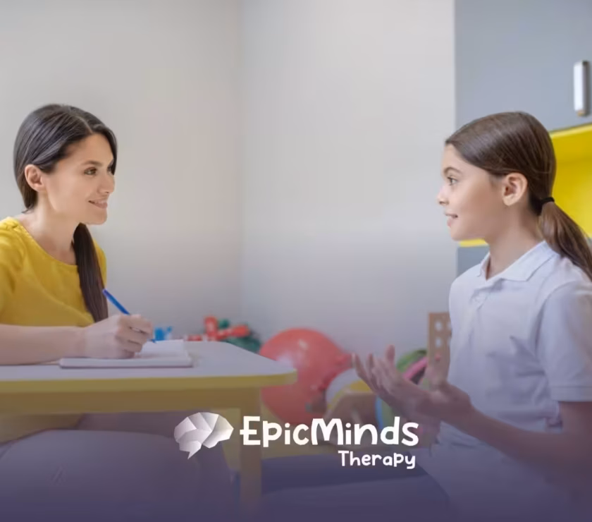 ABA therapist and a child engage in a conversation while sitting at a table during ABA therapy.