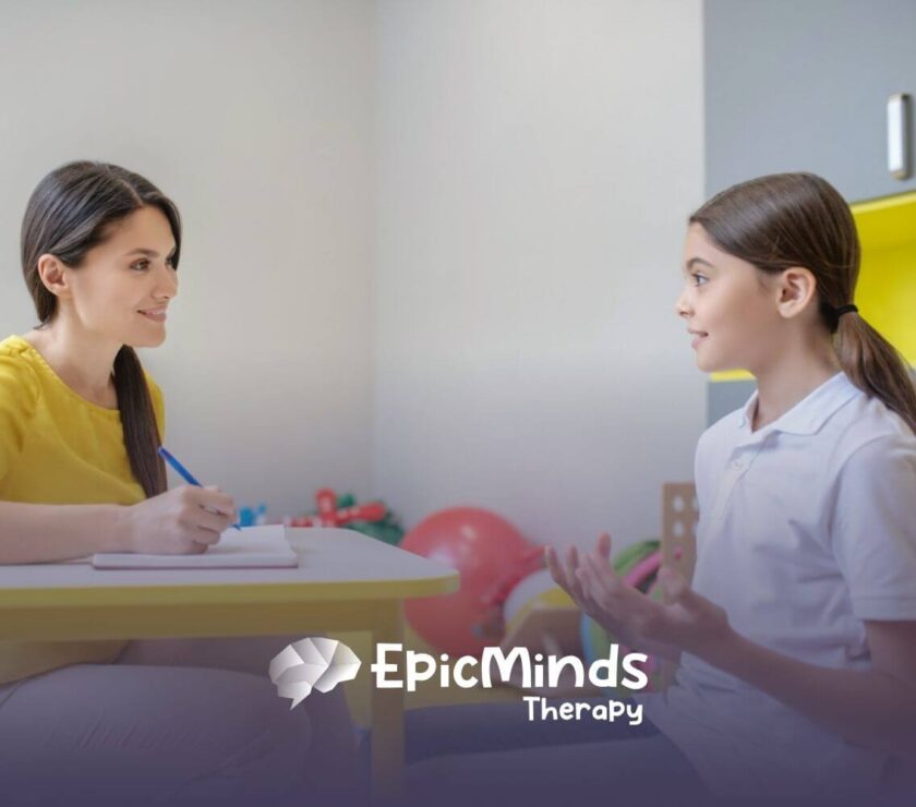 ABA therapist and a child engage in a conversation while sitting at a table during ABA therapy.