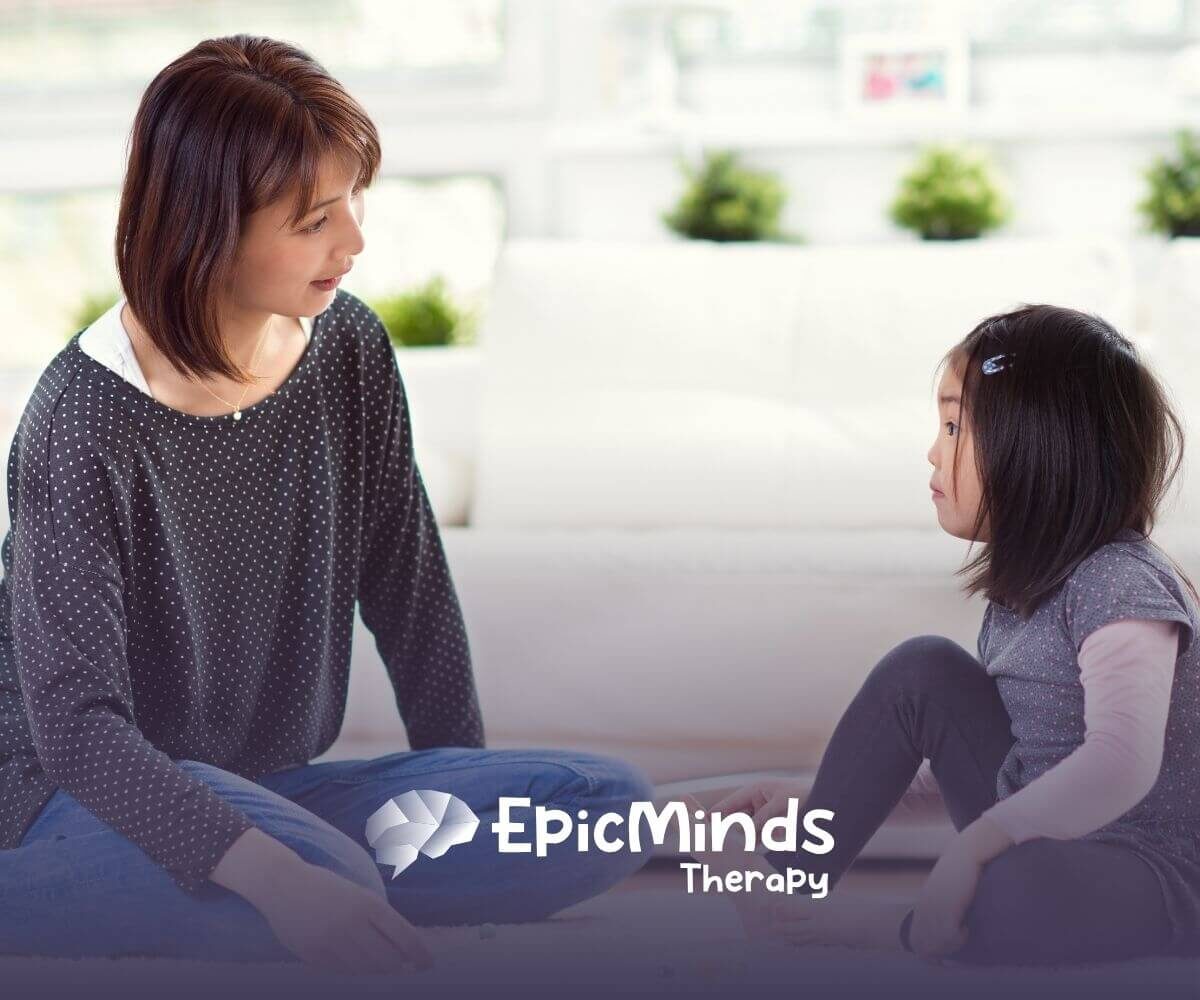 Autistic and BCBA play together on the floor with colorful beads in ABA therapy.