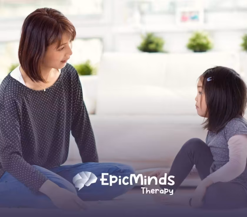 Autistic and BCBA play together on the floor with colorful beads in ABA therapy.