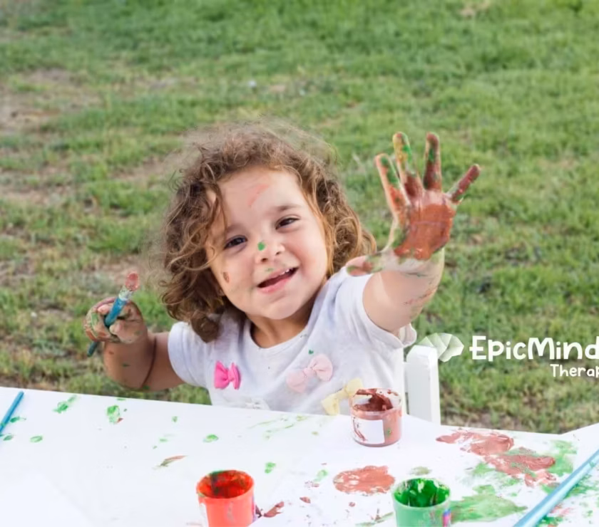 Child enjoying outdoor painting activity during ABA therapy.