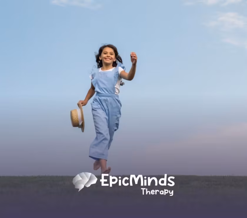 A young girl runs joyfully on a grassy field under a blue sky, holding a straw hat after ABA therapy.