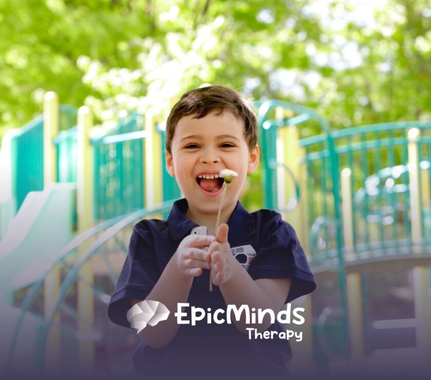 A joyful child holds a white flower, smiling widely against a vibrant playground backdrop. Sunlight filters through green leaves, creating a cheerful atmosphere.