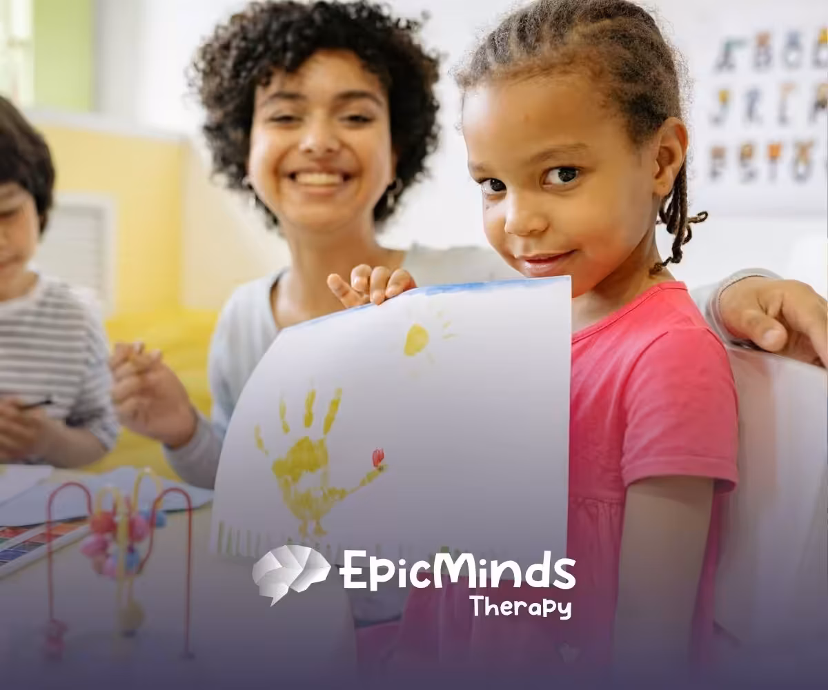 An autistic girl proudly showing her handprint artwork at a classroom during ABA therapy in NC.