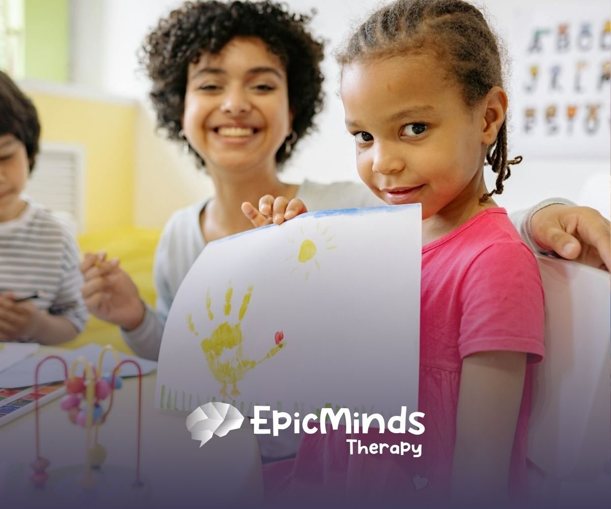 An autistic girl proudly showing her handprint artwork at a classroom during ABA therapy in NC.