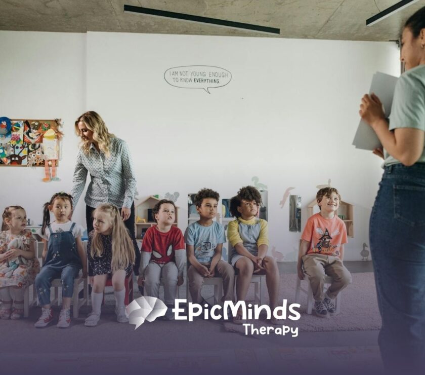 Group of autistic kids sitting in chairs during ABA therapy with an RBT and BCBA standing nearby.