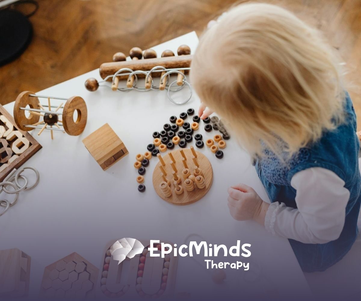 An autistic toddler playing with wooden Montessori toys on a white table during in-home ABA therapy in North Carolina.