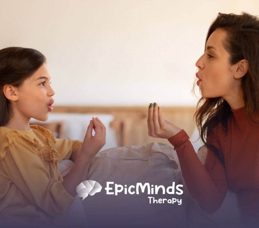 An ABA therapist and autistic girl sitting together, playing a hand game or pronunciation exercise in ABA therapy.