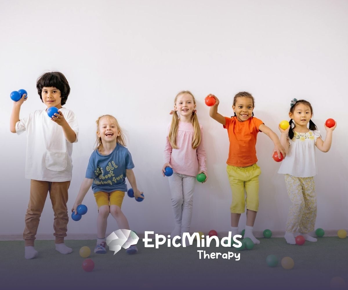 Group of smiling autistic children holding colorful balls in a playful indoor space during ABA therapy in NC.