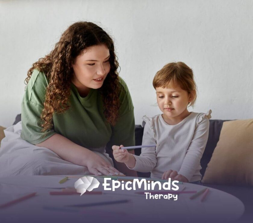 A girl with autism choosing a colored pencil while sitting at a table with an ABA therapist.