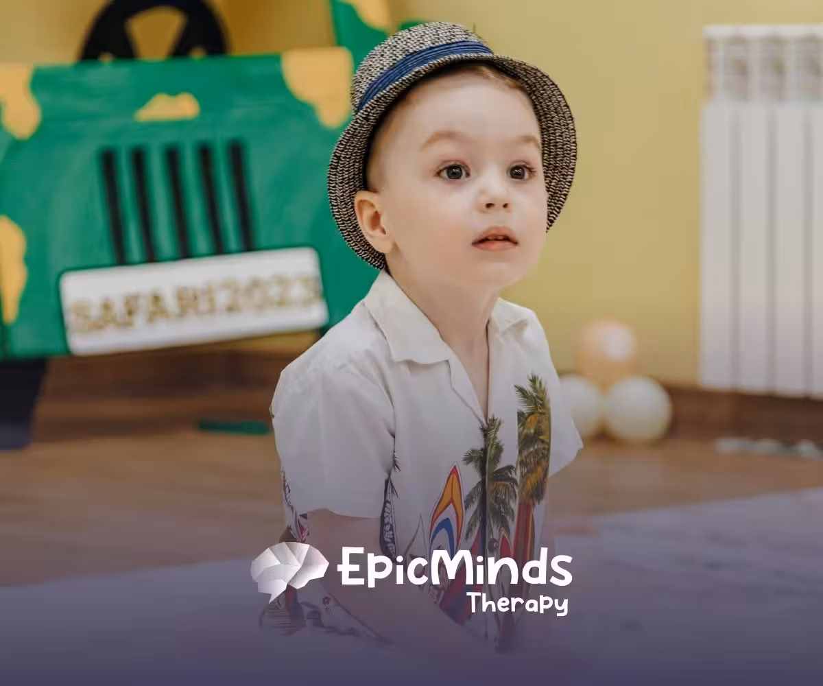 A young child with a curious expression wears a patterned hat and a white shirt with palm leaves. Behind, a safari-themed backdrop and soft lighting set a playful tone.