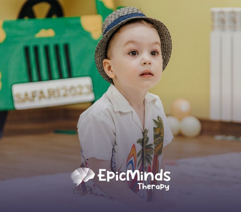 A young child with a curious expression wears a patterned hat and a white shirt with palm leaves. Behind, a safari-themed backdrop and soft lighting set a playful tone.