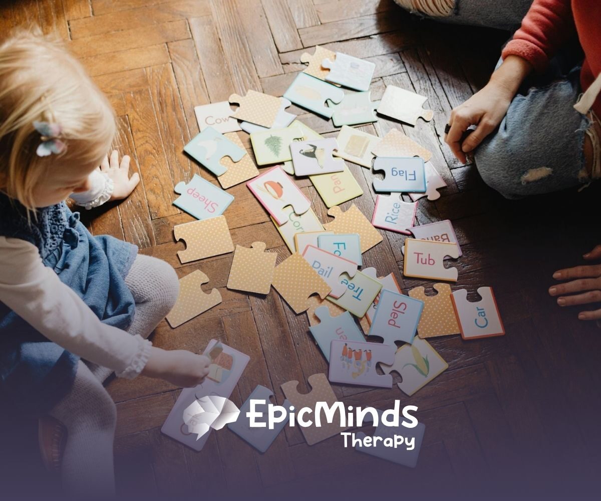 An autistic toddler matching word puzzle pieces on a wooden floor with an RBT during in-home ABA therapy in NC.