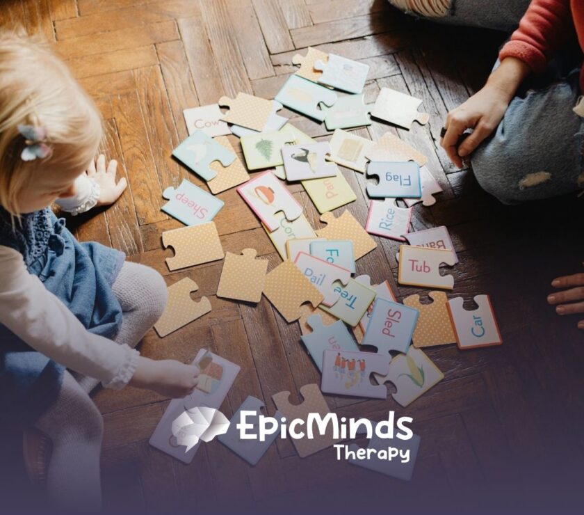 An autistic toddler matching word puzzle pieces on a wooden floor with an RBT during in-home ABA therapy in NC.