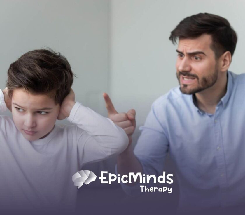 A boy with autism covering his ears while a man points and scolds him.