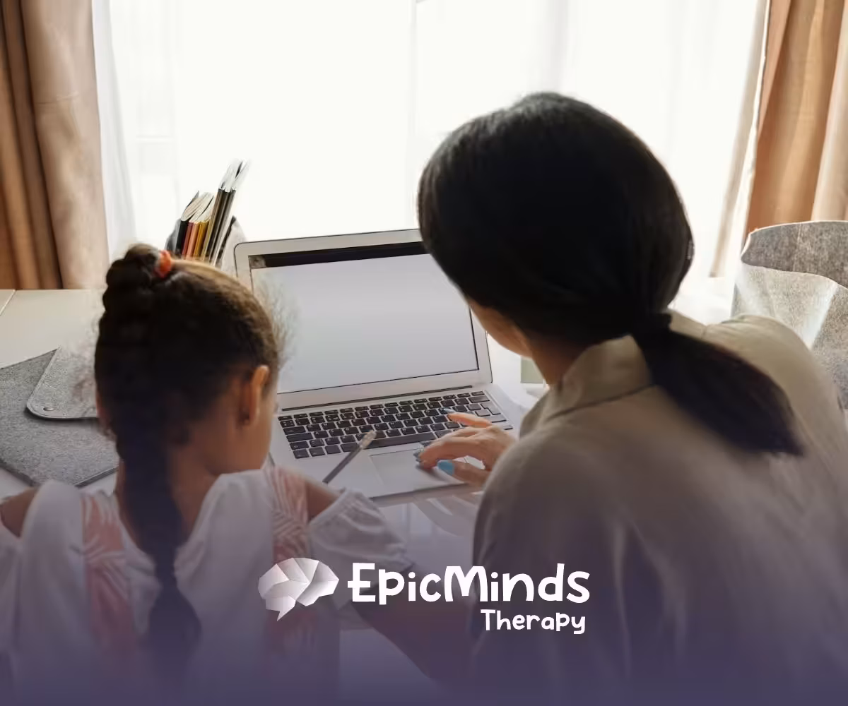 An autistic child and RBT using a laptop at a table to learn a second language during ABA therapy in North Carolina.