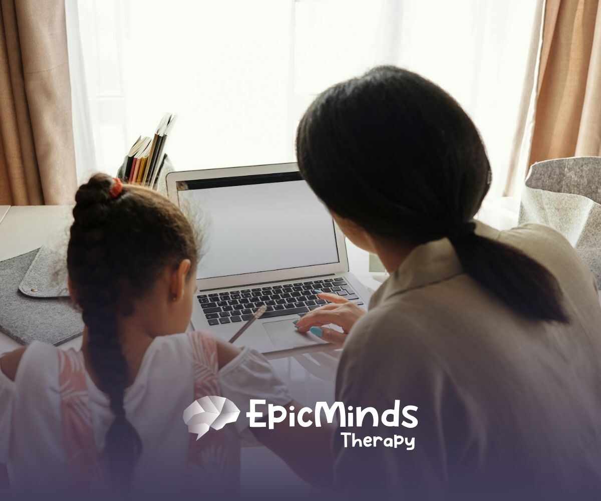 An autistic child and RBT using a laptop at a table to learn a second language during ABA therapy in North Carolina.