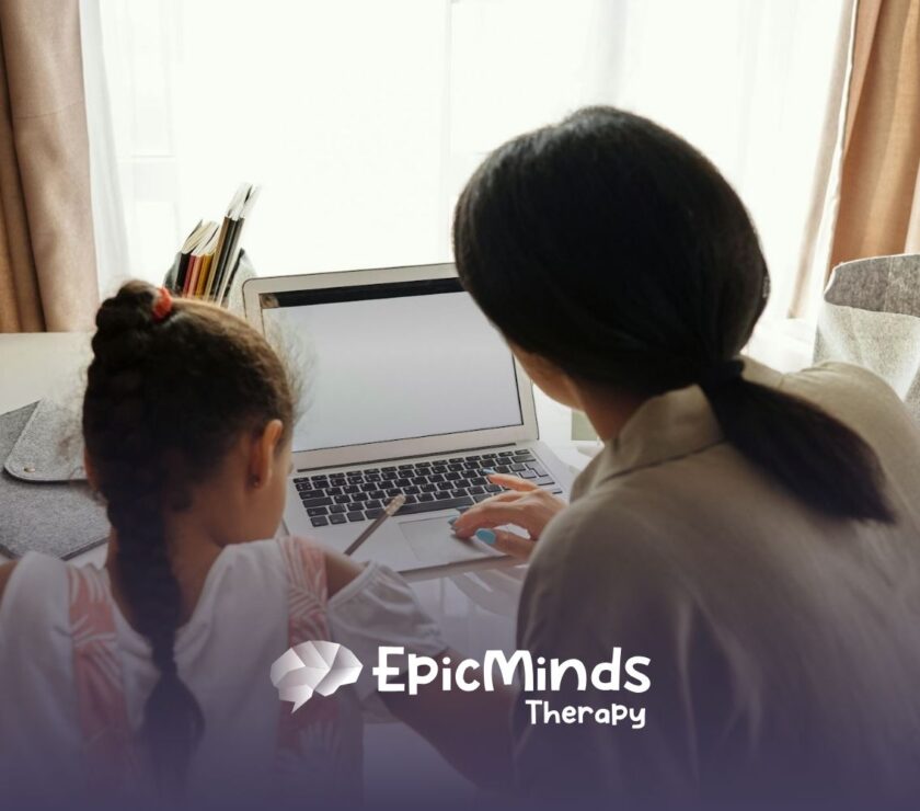 An autistic child and RBT using a laptop at a table to learn a second language during ABA therapy in North Carolina.