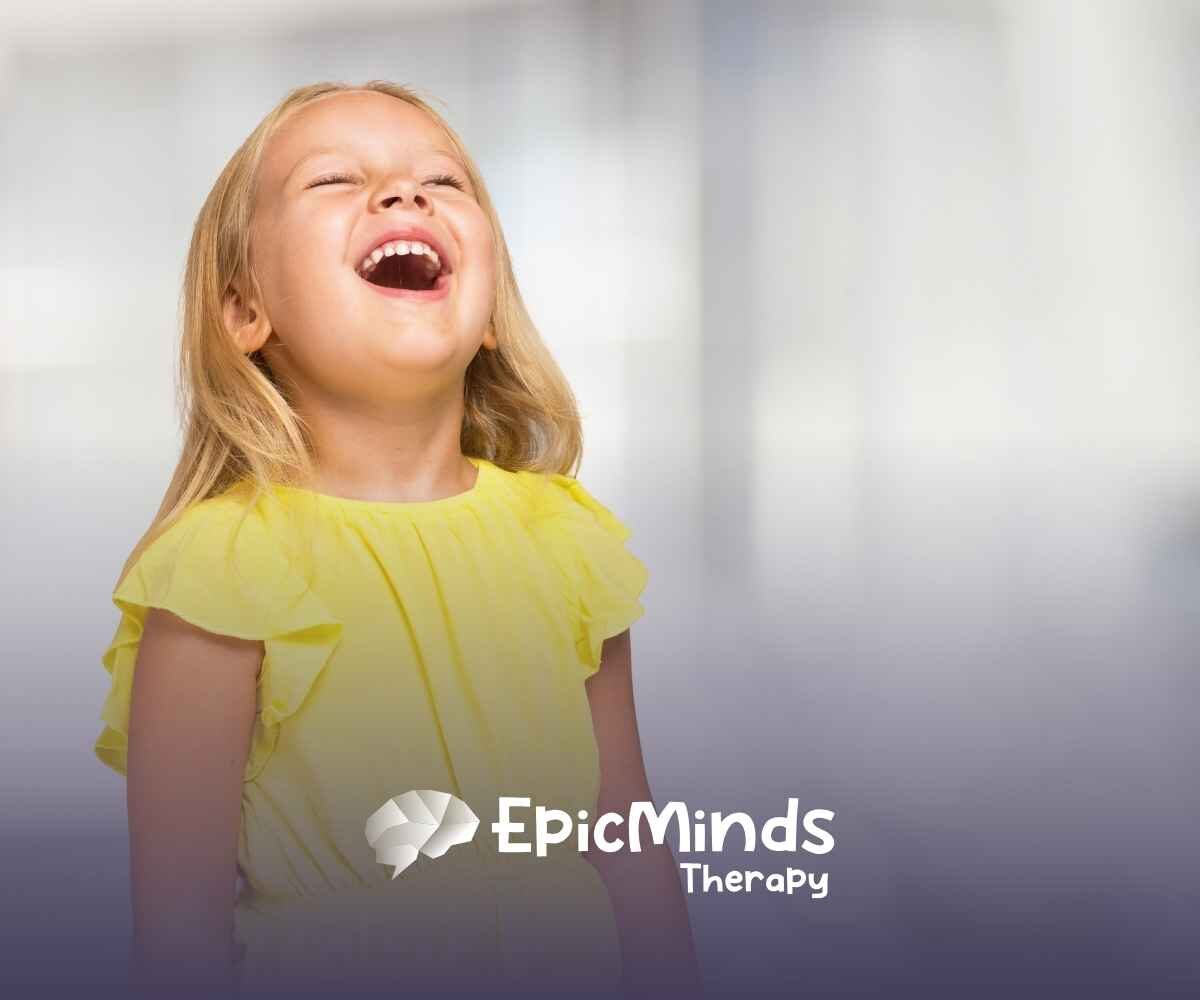 A joyful young girl in a bright yellow dress laughs with her head tilted back, set against a blurred, light background.