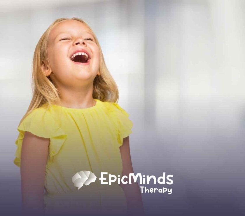 A joyful young girl in a bright yellow dress laughs with her head tilted back, set against a blurred, light background.