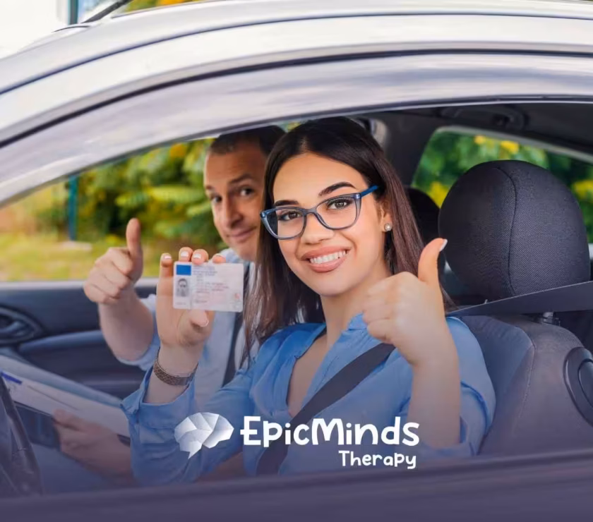 Smiling woman in a car holds up a driver's license with a thumbs-up gesture. A man beside her also gives a thumbs-up.