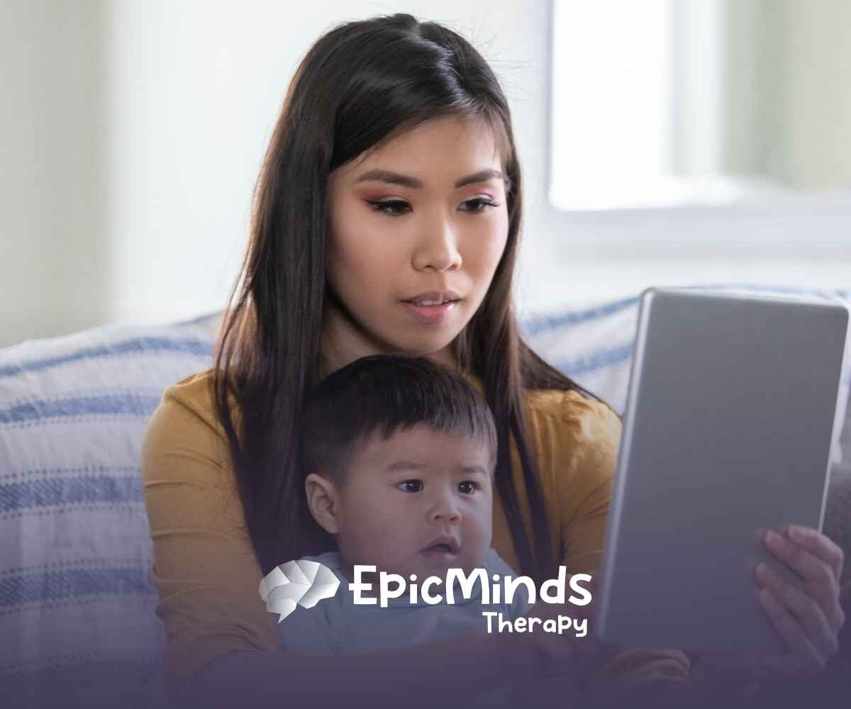 A woman and baby sit on a couch, engaged with a tablet. The woman looks focused, while the baby gazes at the screen. The setting is cozy and calm.