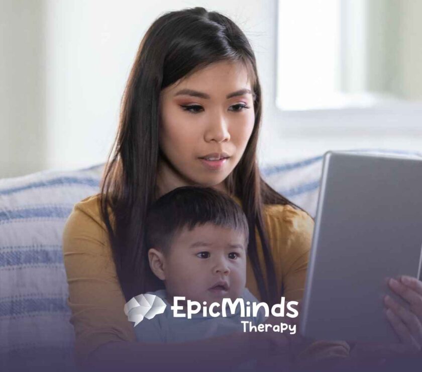 A woman and baby sit on a couch, engaged with a tablet. The woman looks focused, while the baby gazes at the screen. The setting is cozy and calm.