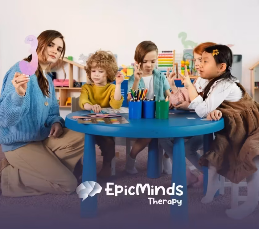 BCBA showing cutout number to children with autism at classroom table.