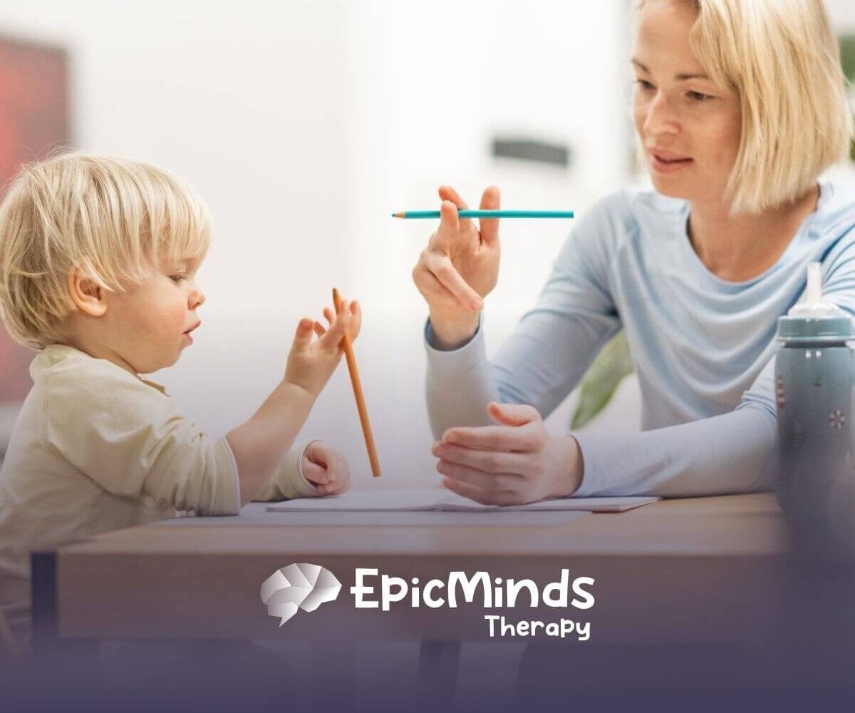 BCBA teaching toddler with autism to draw with pencils in ABA therapy.