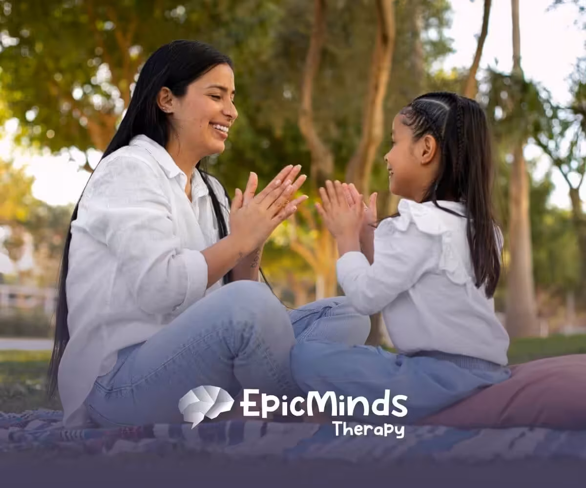 BCBA and girl with autism playing hand-clap game in the park.