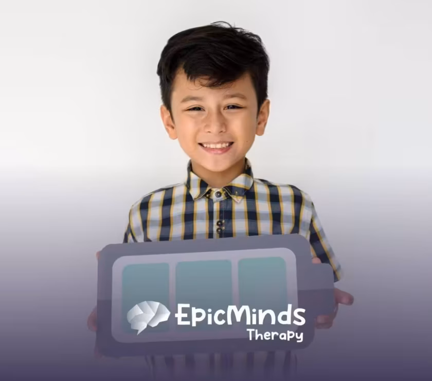 Smiling boy with autism holding a paper cutout of a battery symbol.
