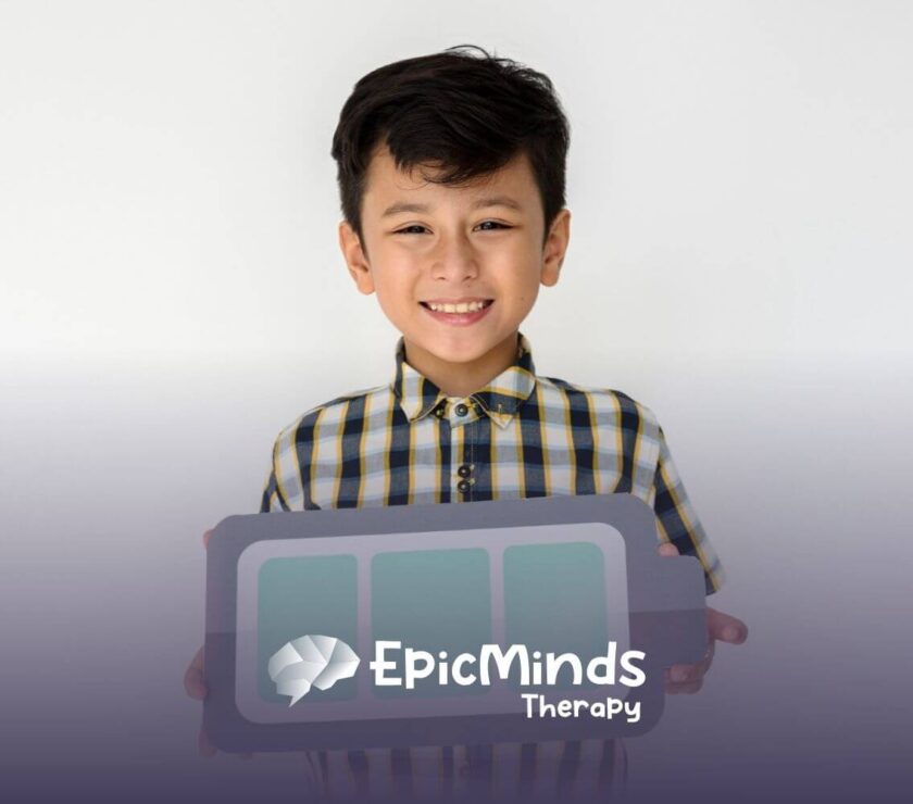 Smiling boy with autism holding a paper cutout of a battery symbol.
