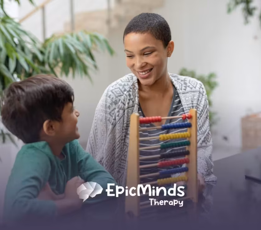 Smiling BCBA teaching young boy with an abacus in ABA therapy.