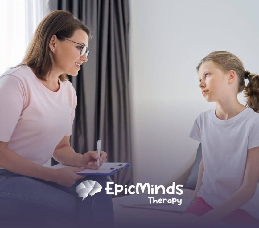 A female BCBA talking to a young girl with autism holding a clipboard in ABA therapy.