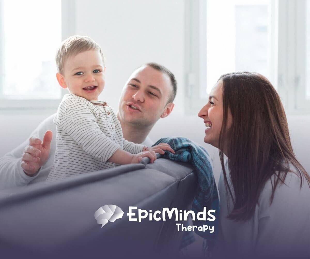 Parents smiling while playing with their baby boy on a couch in ABA parent training.