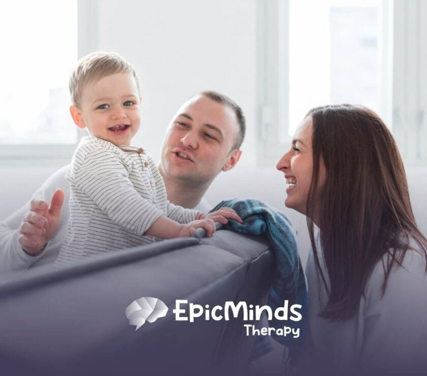 Parents smiling while playing with their baby boy on a couch in ABA parent training.