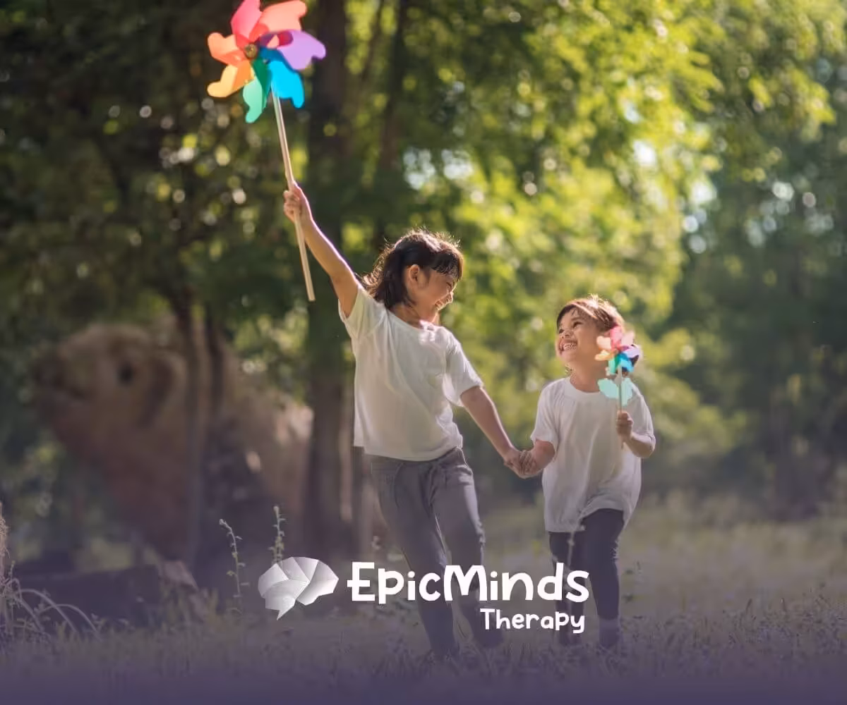 Two children with autism holding hands and playing with pinwheels outdoors.