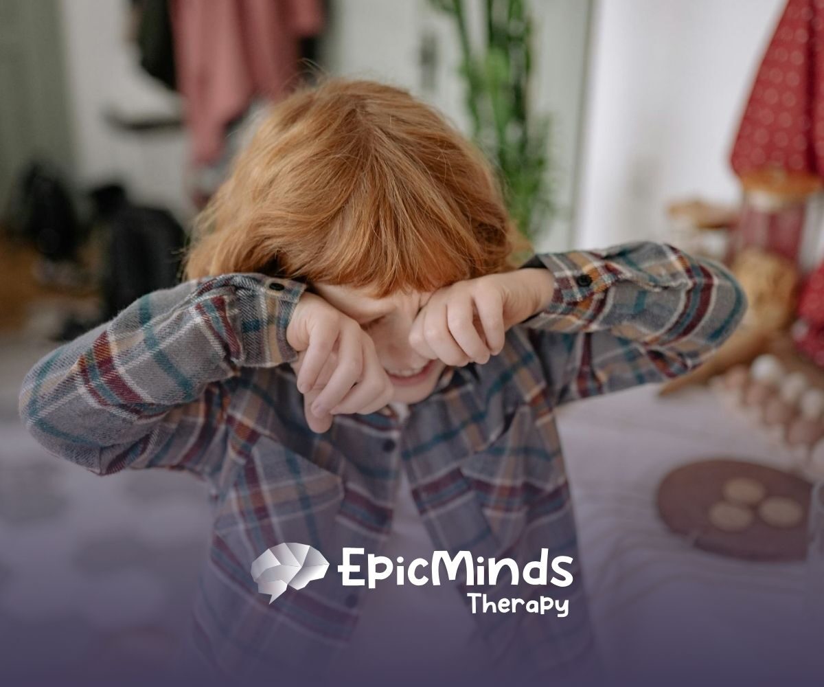 An autistic child with red hair getting upset and rubbing his eyes while standing in a kitchen in North Carolina.