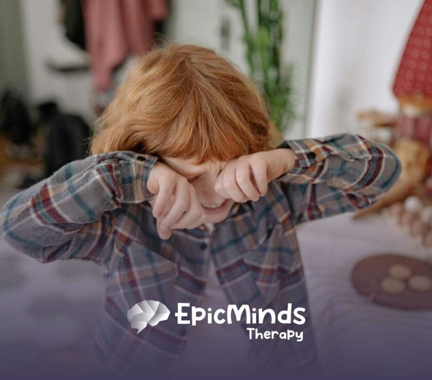 An autistic child with red hair getting upset and rubbing his eyes while standing in a kitchen in North Carolina.