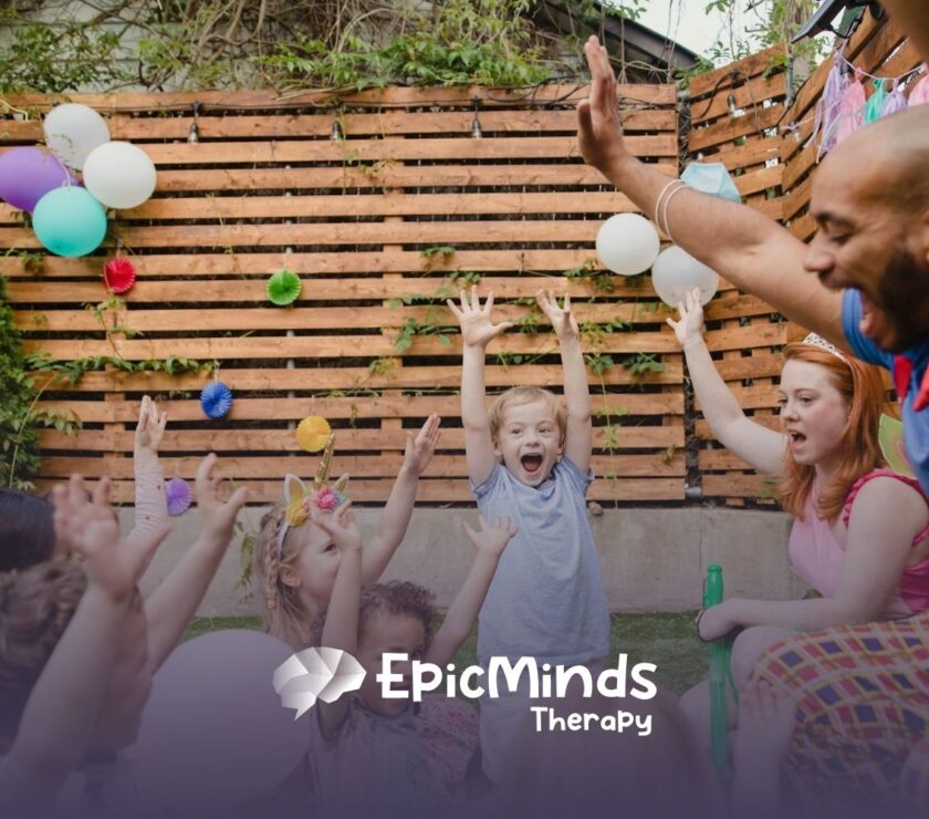 Group of autistic children, RBTs, and BCBAs raising hands joyfully during play-based ABA therapy in North Carolina.