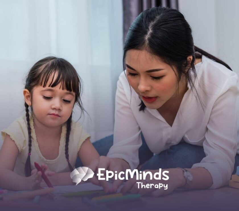 Female BCBA helping autistic girl with coloring activity on the floor in ABA therapy.