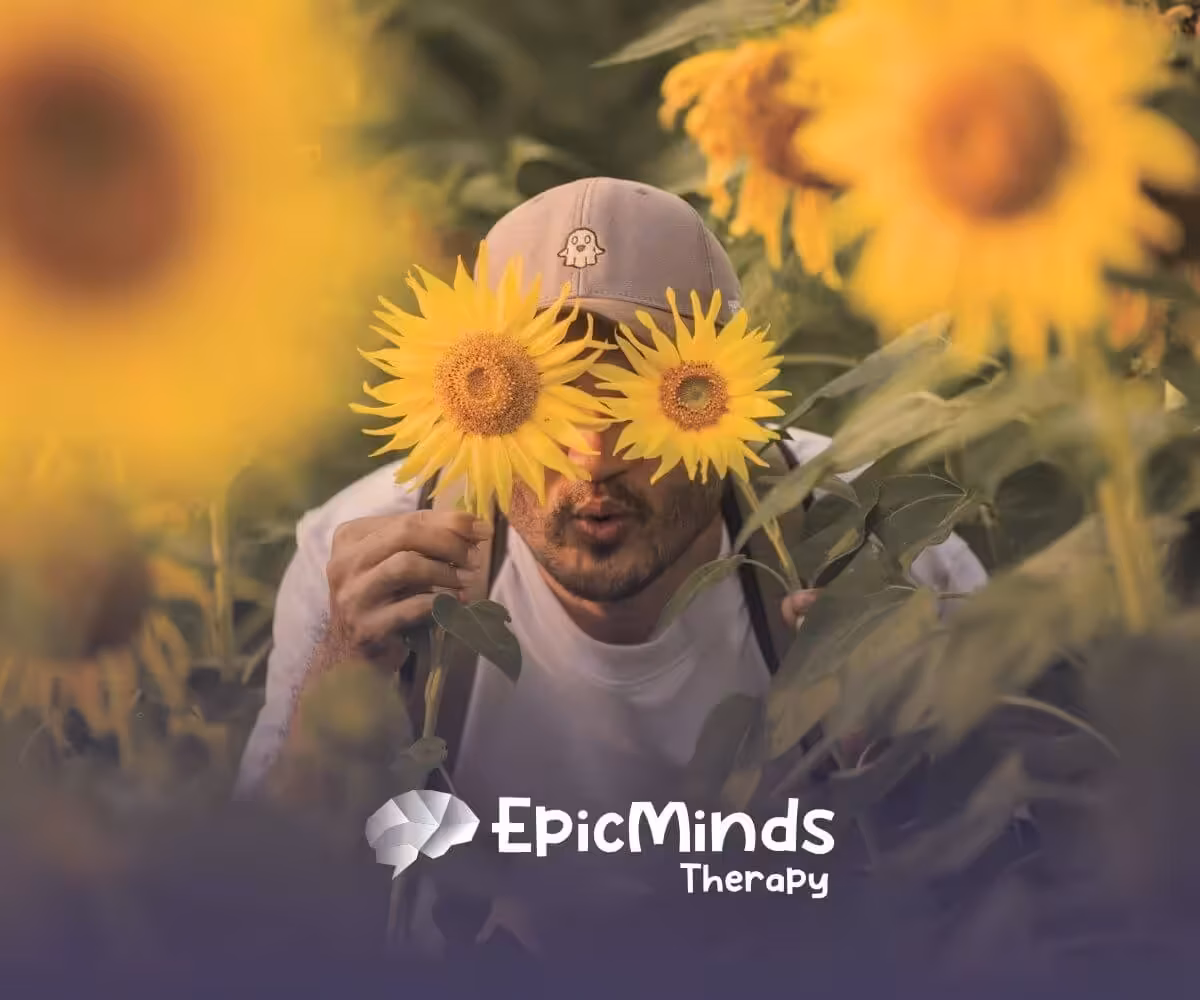 The autistic gentlemen playfully hiding behind sunflowers in a field after his ABA Therapy in North Carolina.