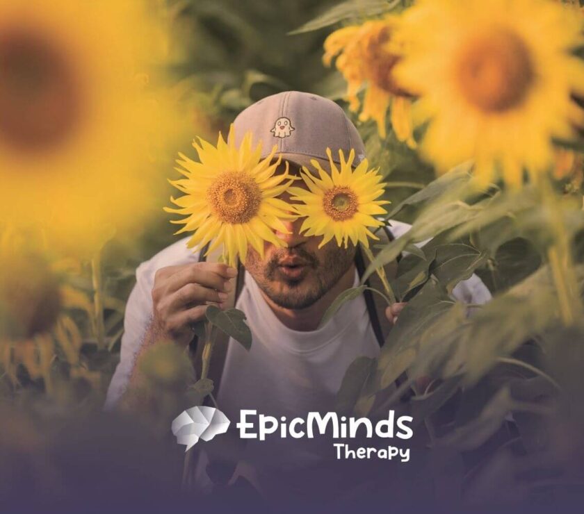 The autistic gentlemen playfully hiding behind sunflowers in a field after his ABA Therapy in North Carolina.