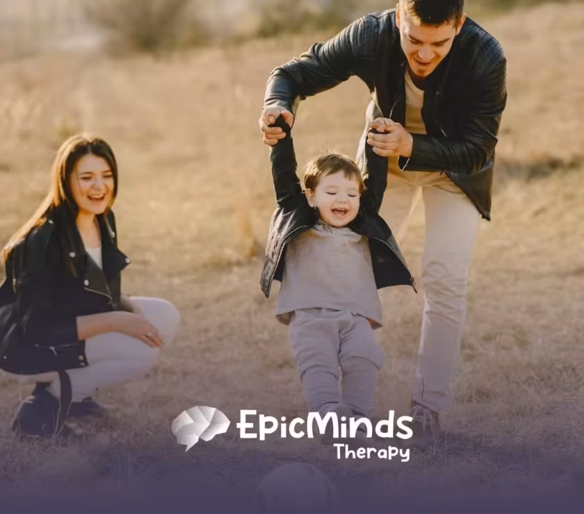 Mom and dad kick a ball with their giggling child in a grassy field on a sunny afternoon in North Carolina.