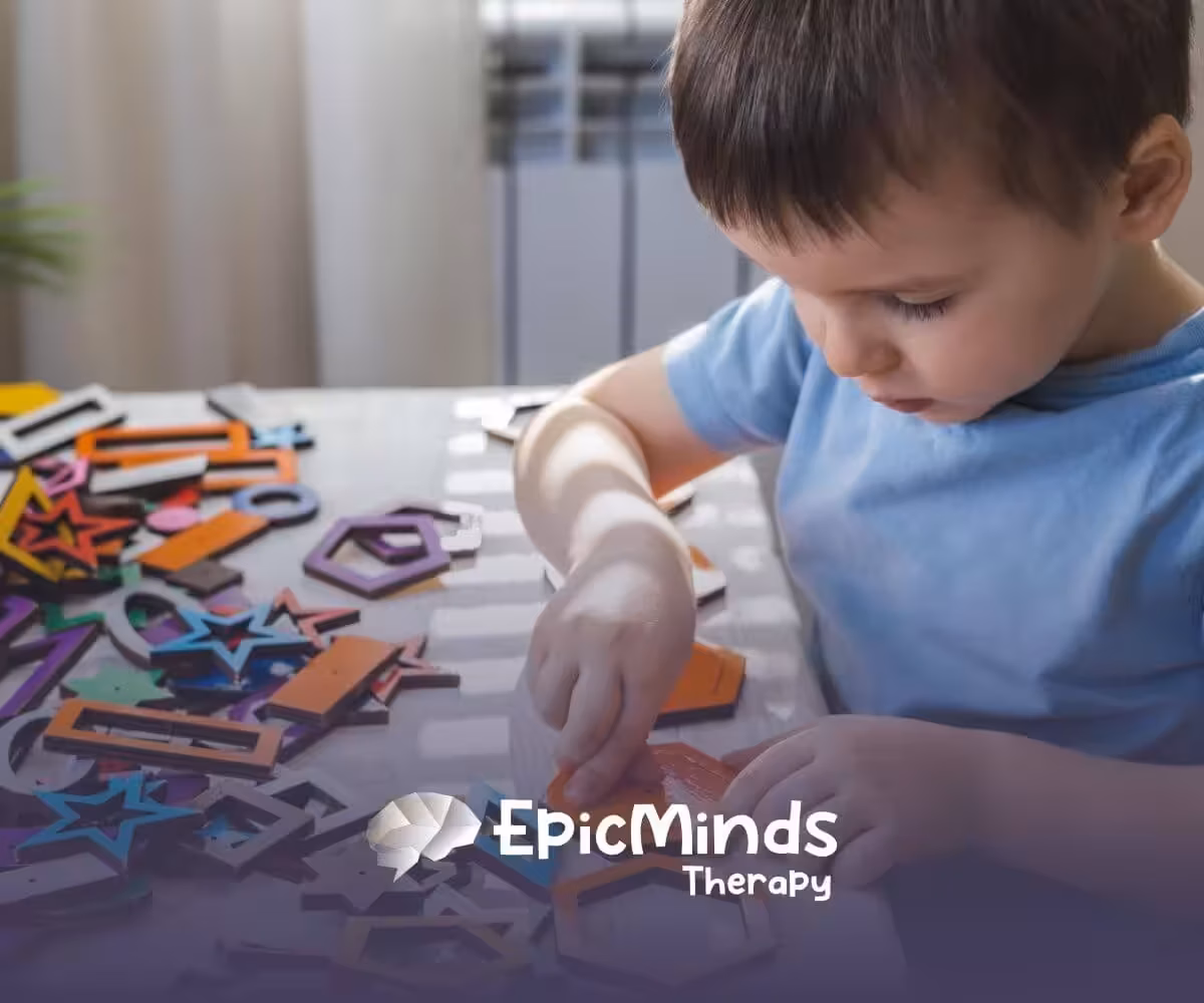 Child with autism focusing on colorful wooden shapes during ABA therapy.