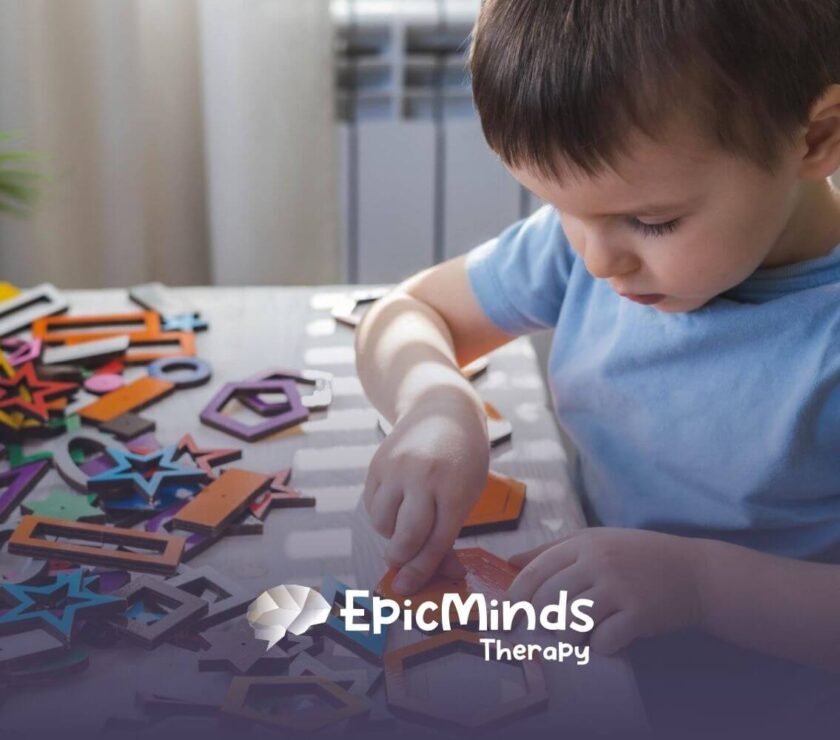 Child with autism focusing on colorful wooden shapes during ABA therapy.