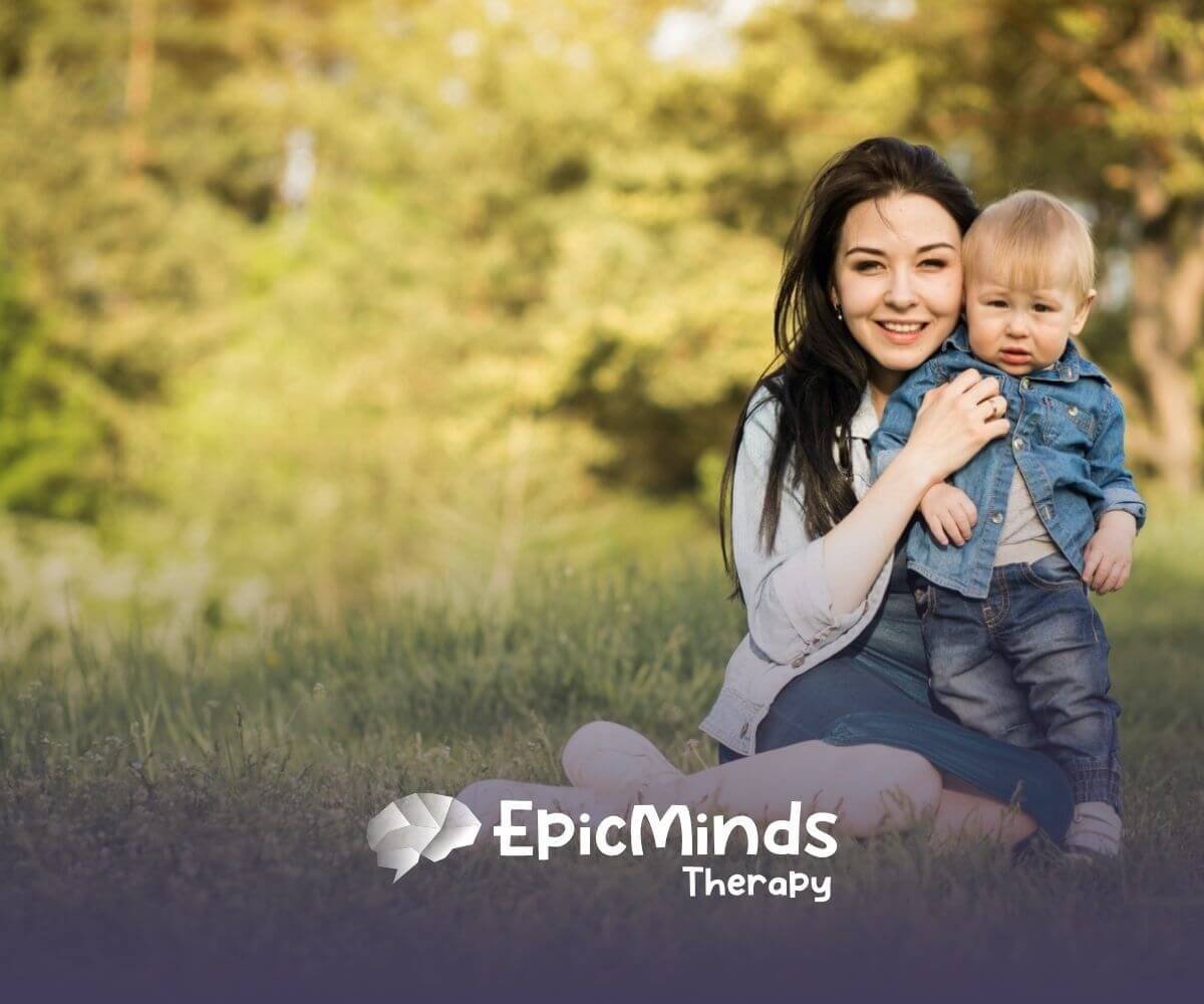 Mother sitting on grass with her young child enjoying outdoor time after ABA therapy session.