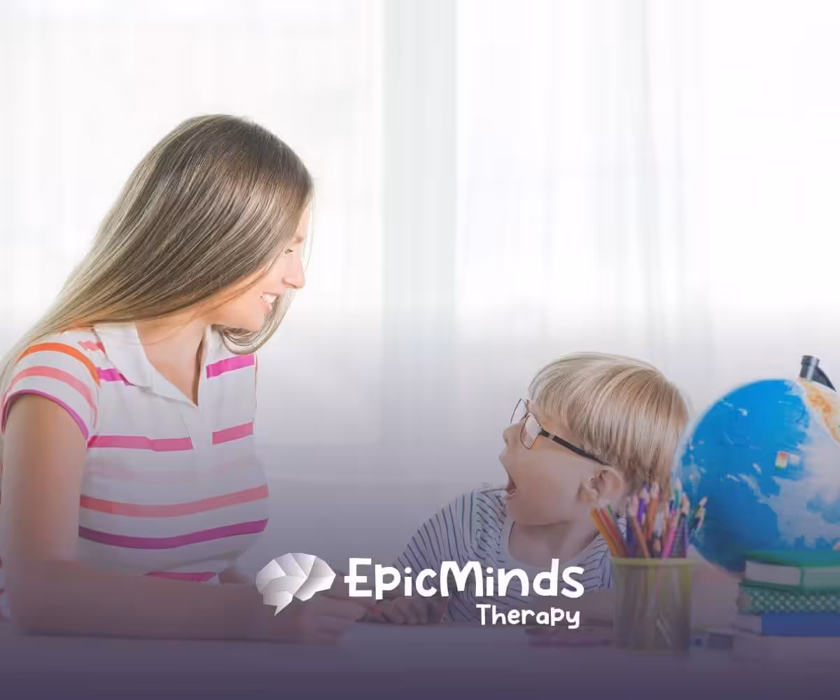 Therapist smiling and engaging with young boy during ABA therapy activity.