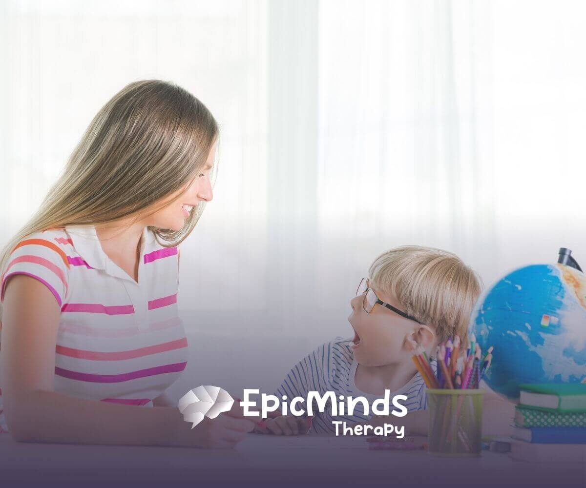 Therapist smiling and engaging with young boy during ABA therapy activity.